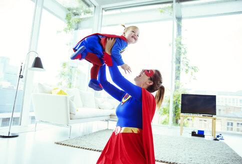 Superheld spielt mit Baby im Wohnzimmer - CAIF13949