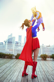 Superheldenmutter spielt mit ihrer Tochter auf dem Dach der Stadt - CAIF13963