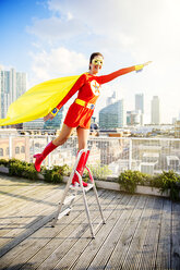 Superhero standing on stepladder on city rooftop - CAIF13971