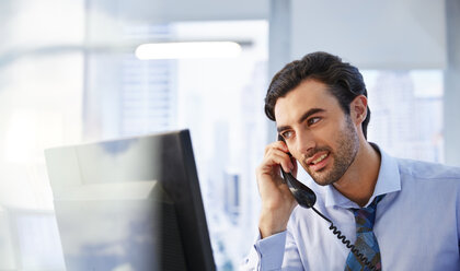 Mann benutzt Festnetztelefon im Büro - CAIF13988