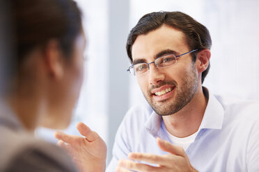 Lächelnder Mann mit Brille im Büro mit einem Kunden - CAIF14005