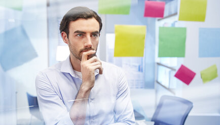 Büroangestellte hinter Glas mit bunten Haftnotizen denken - CAIF14033