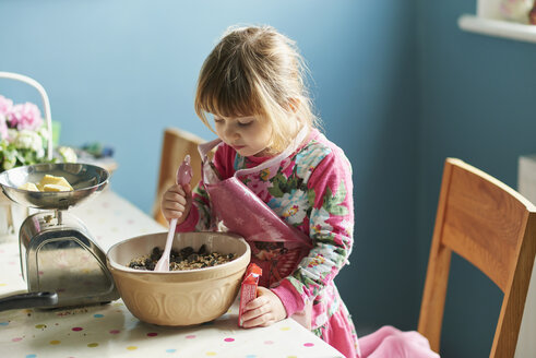 Neugieriges Mädchen beim Backen mit Rührschüssel in der Küche - CAIF14043