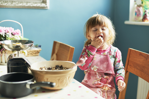 Girl tasting baking ingredients in kitchen stock photo