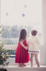Mädchen auf Fensterbrett unter Weihnachtsschmuck - CAIF14049
