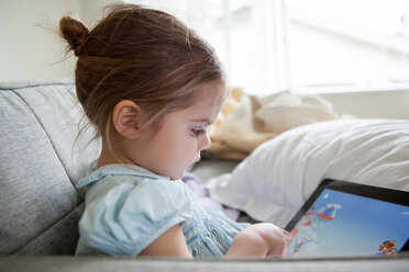 Girl using digital tablet on sofa - CAIF14057