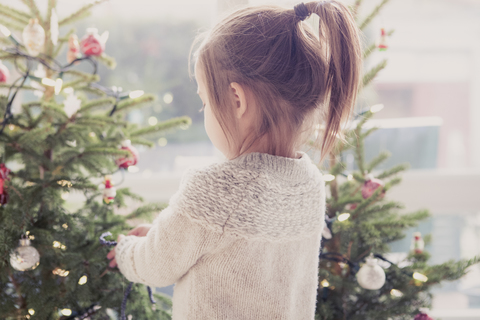 Mädchen schmückt Weihnachtsbaum, lizenzfreies Stockfoto