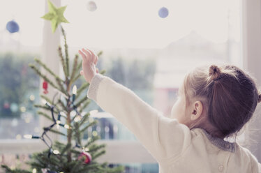 Girl reaching for start on Christmas tree - CAIF14060