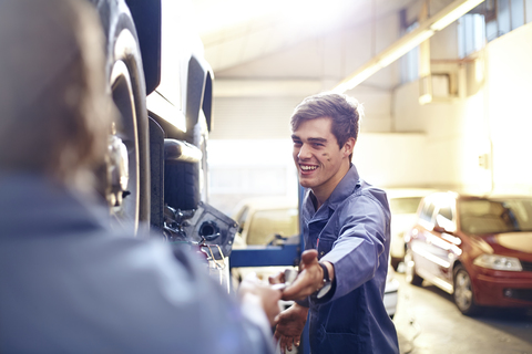 Mechaniker greift nach Werkzeug in der Autowerkstatt, lizenzfreies Stockfoto