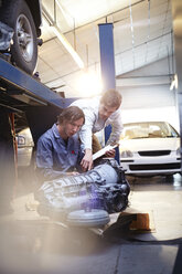 Mechaniker und Kunde bei der Untersuchung eines Motorteils in einer Autowerkstatt - CAIF14086