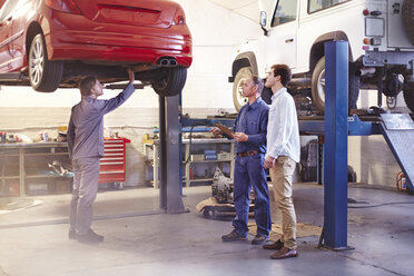 Mechaniker im Gespräch mit einem Kunden in einer Autowerkstatt - CAIF14092