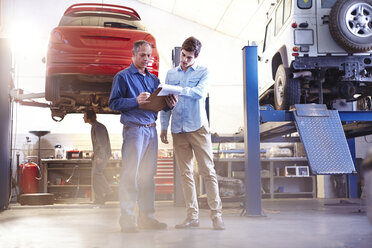 Mechaniker mit Klemmbrett im Gespräch in der Autowerkstatt - CAIF14095