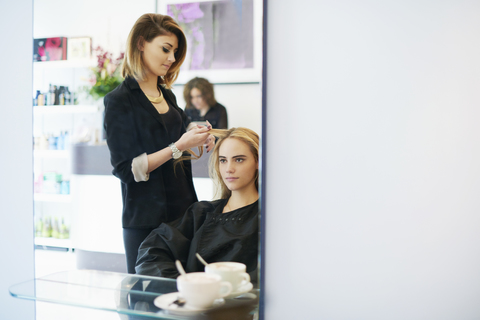 Friseur, der einer Kundin im Salon die Haare lockt, lizenzfreies Stockfoto