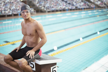 Swimmer sitting on starting block at poolside - CAIF14161