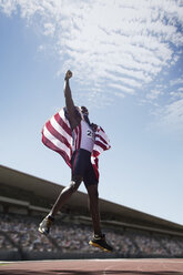 Amerikanischer Leichtathlet mit amerikanischer Flagge, der auf der Strecke jubelt - CAIF14185