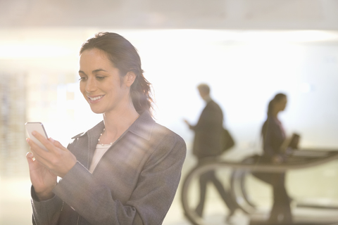 Lächelnde Geschäftsfrau, die mit ihrem Handy SMS schreibt, lizenzfreies Stockfoto