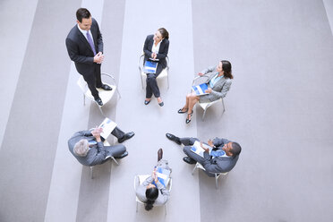 Hoher Blickwinkel von Geschäftsmann stehend auf Stuhl im Kreis mit Mitarbeitern - CAIF14242