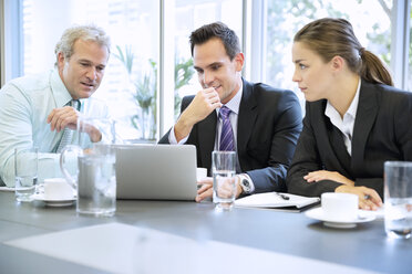 Geschäftsleute teilen sich einen Laptop in einer Besprechung - CAIF14243