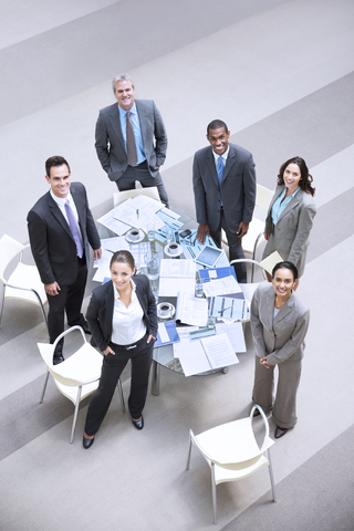 Hochformatiges Porträt von lächelnden Geschäftsleuten am Tisch, lizenzfreies Stockfoto