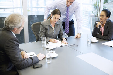 Business people reviewing paperwork in meeting - CAIF14248