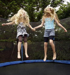 Girls jumping on trampoline outdoors - CAIF14259