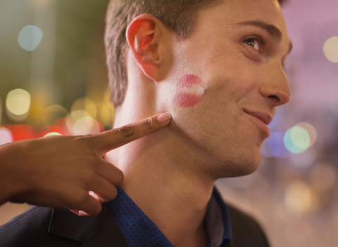 Mann posiert mit Lippenstiftabdruck auf der Wange in der Stadt, lizenzfreies Stockfoto