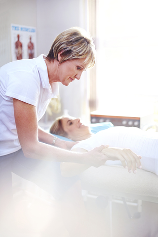 Physiotherapeutin massiert die Hand einer Frau, lizenzfreies Stockfoto