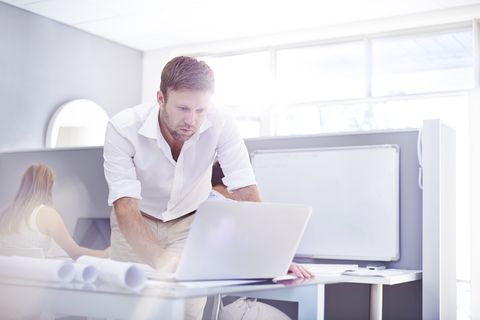 Architekt benutzt Laptop in sonnigem Büro, lizenzfreies Stockfoto