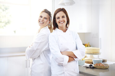 Portrait confident chefs back to back in kitchen - CAIF14419