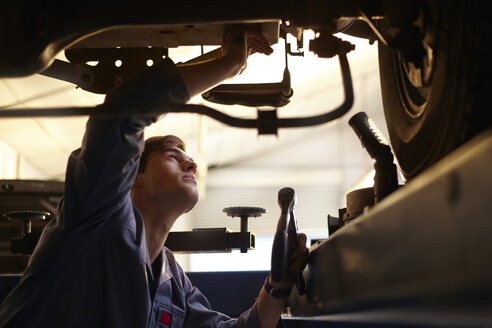 Mechaniker bei der Arbeit unter einem Auto in einer Autowerkstatt - CAIF14431