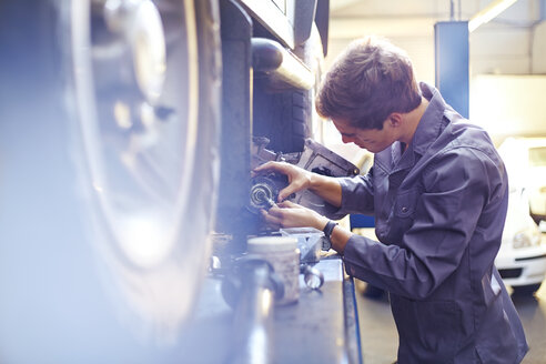 Mechaniker, der ein Teil in einer Autowerkstatt untersucht - CAIF14434