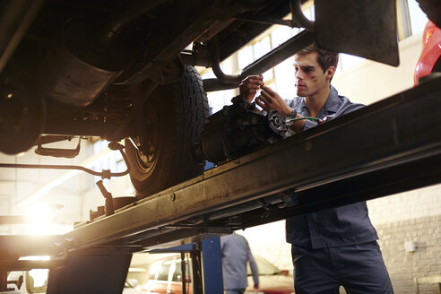 Mechaniker bei der Arbeit unter einem Auto in einer Autowerkstatt - CAIF14435