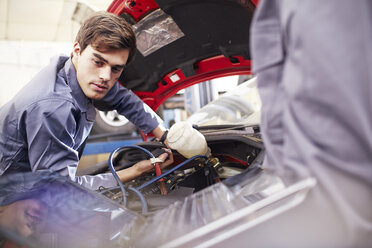 Mechanic working on car engine in auto repair shop - CAIF14436