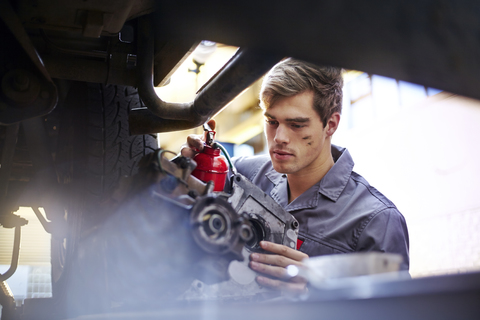 Mechaniker ölt Teil in Autowerkstatt, lizenzfreies Stockfoto