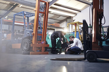 Mechaniker arbeiten in der Nähe eines Gabelstaplers in einer Autowerkstatt - CAIF14446