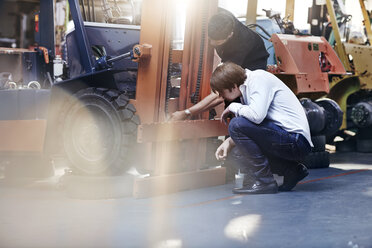 Mechaniker und Kunde bei der Prüfung eines Gabelstaplers in einer Autowerkstatt - CAIF14451