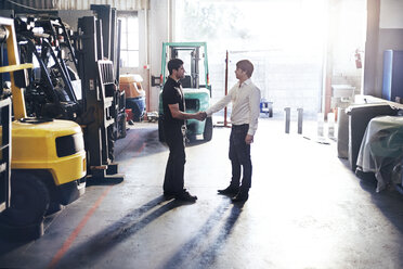 Mechanic and customer handshaking in auto repair shop - CAIF14453