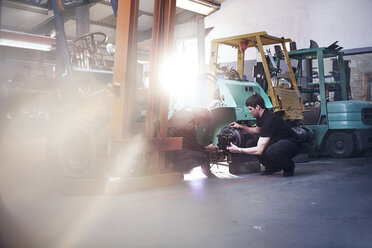Mechanics examining forklift in auto repair shop - CAIF14455