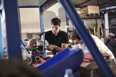 Mechaniker bei der Prüfung eines Teils in der Autowerkstatt - CAIF14459
