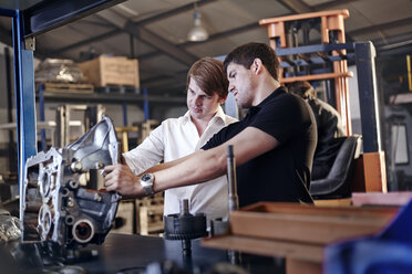 Mechanic and customer examining part in auto repair shop - CAIF14466