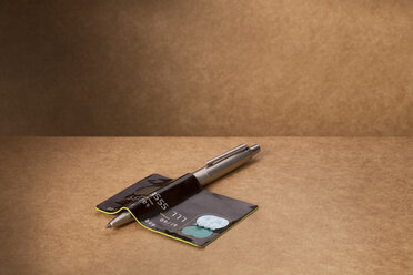 Kreditkarte über den Stift auf dem Tresen gebogen - CAIF14476