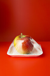 Close up of apple shrink wrapped in plastic - CAIF14488