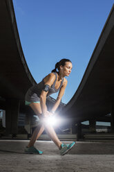 Woman stretching before exercising on city street - CAIF14512