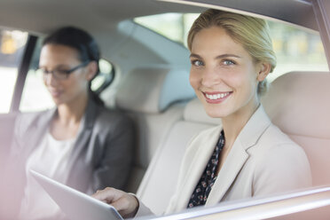 Businesswoman using digital tablet in car back seat - CAIF14530