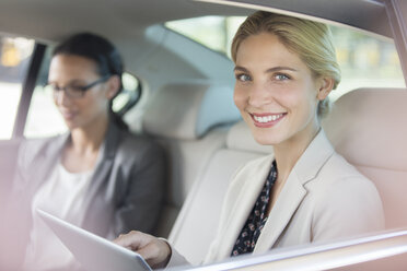 Geschäftsfrau mit digitalem Tablet auf dem Rücksitz eines Autos - CAIF14530