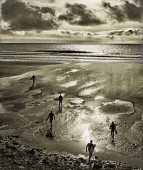 Silhouetten von Surfern, die mit Surfbrettern am Strand von Perranuthnoe spazieren gehen - CAIF14533