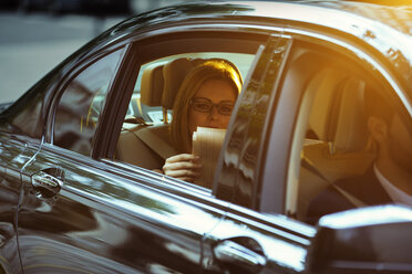 Geschäftsfrau liest Zeitung auf dem Rücksitz eines Autos - CAIF14575