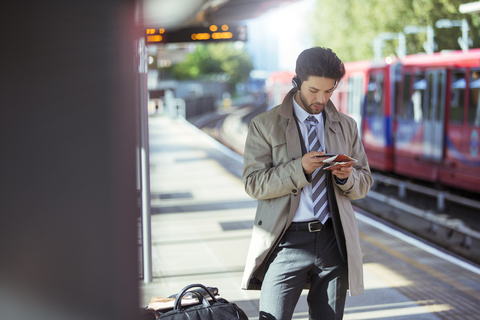 Geschäftsmann benutzt Mobiltelefon im Bahnhof, lizenzfreies Stockfoto