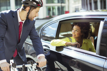 Businessman on bicycle talking to woman in car - CAIF14586