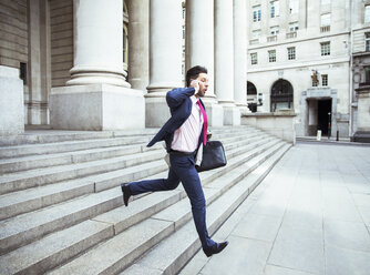 Businessman on cell phone running on city staircase - CAIF14589